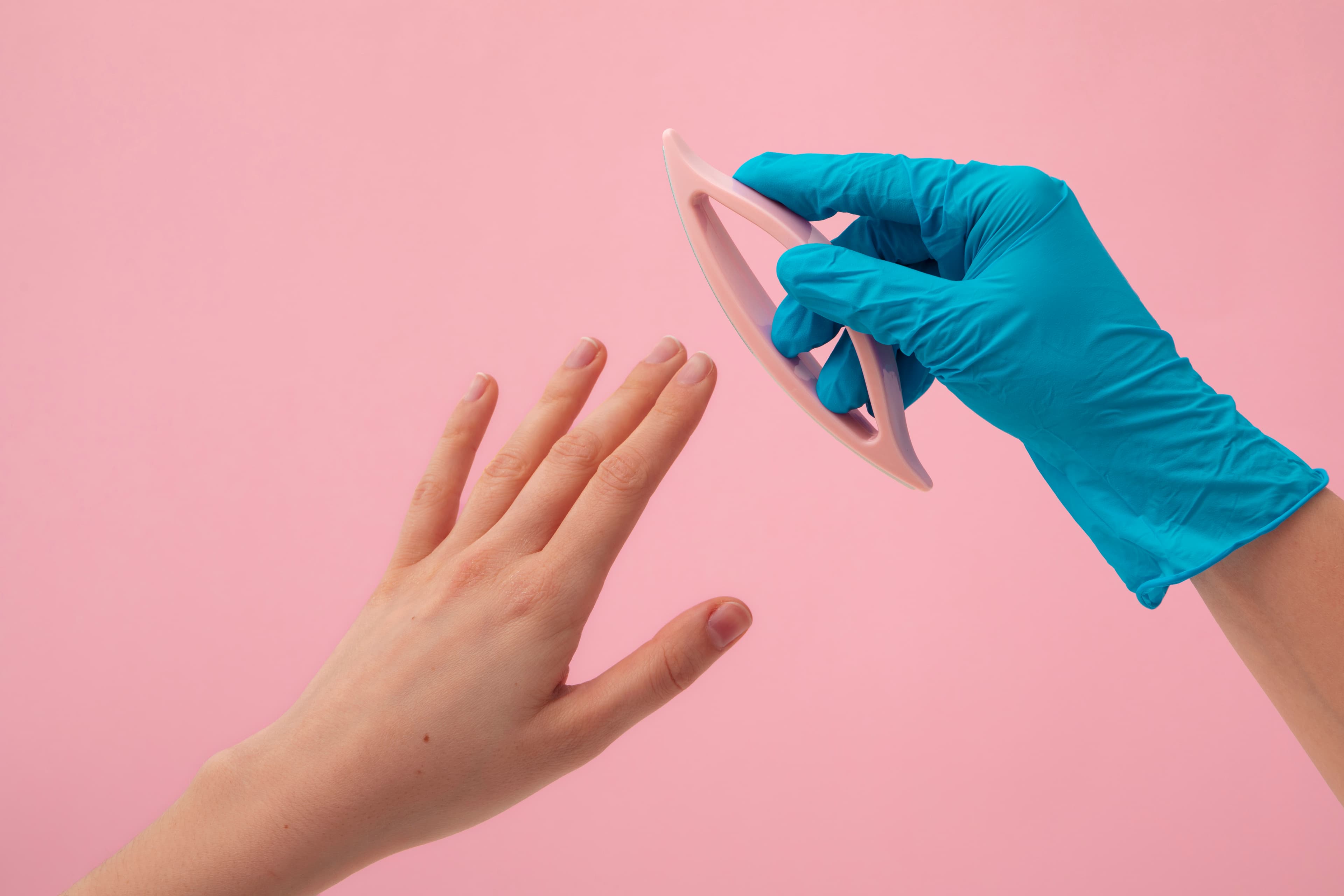 Gloved hands refining a client’s nails